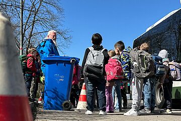 Mann mit Bart steht beim Bussicherheitstraining der swa vor Kindern. Im Hintergrund ist ein Bus 