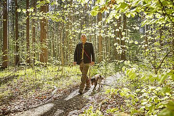 Förster läuft mit seinem Hund durch den Wald und betrachtet die Bäume. - Ein Klick auf das Bild führt zur vergrößerten Fotoansicht.