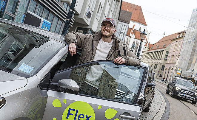 Mann steht hinter geöffneter Tür eines Carsharing-Flex Autos 