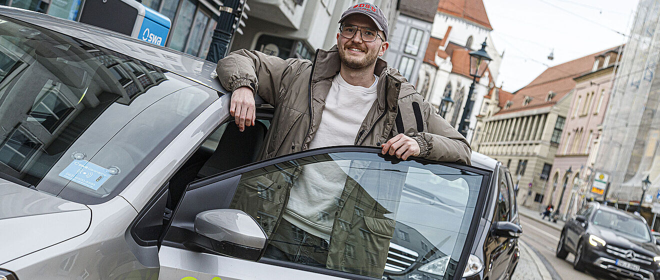Mann steht hinter geöffneter Tür eines Carsharing-Flex Autos 