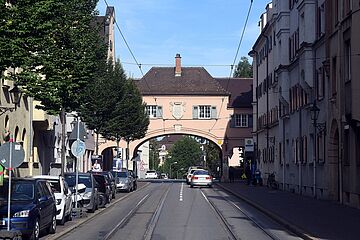 Das Fischertor. Links stehen parkende Autos, rechts ist ein Gehweg mit einer Haltestelle. - Ein Klick auf das Bild führt zur vergrößerten Fotoansicht.
