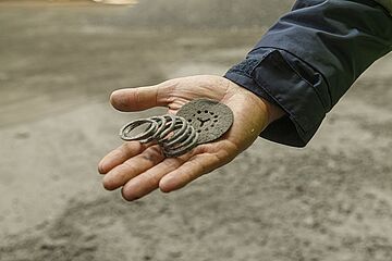 Hand hält Metallringe aus der Mülltrennung. Ein Klick sorgt für eine Großansicht des Bildes.