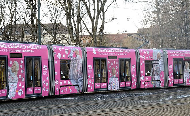 Eine Straßenbahn in den Mozartstadt-Farben Weiß und Pink