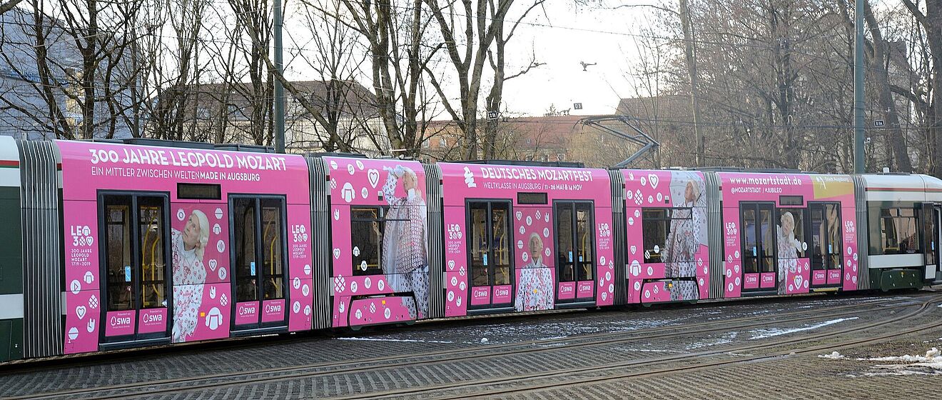 Eine Straßenbahn in den Mozartstadt-Farben Weiß und Pink