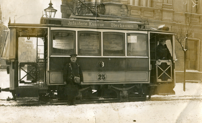 Historische Fotoaufnahme eines Straßenbahnfahrers vor einer Tram
