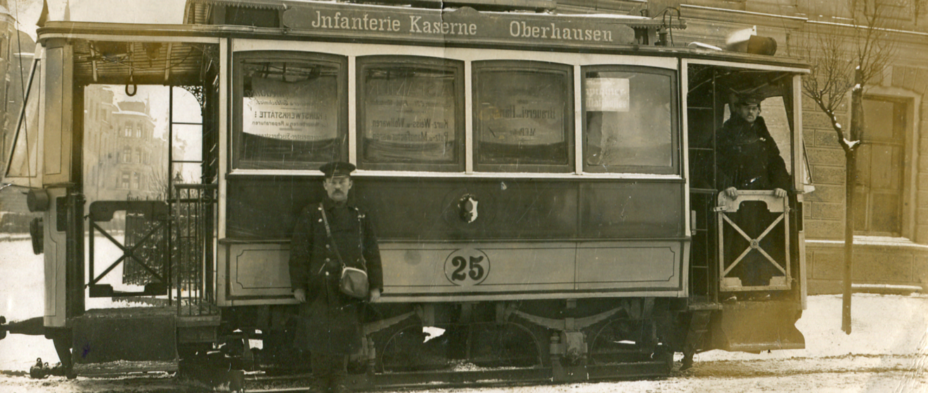 Historische Fotoaufnahme eines Straßenbahnfahrers vor einer Tram