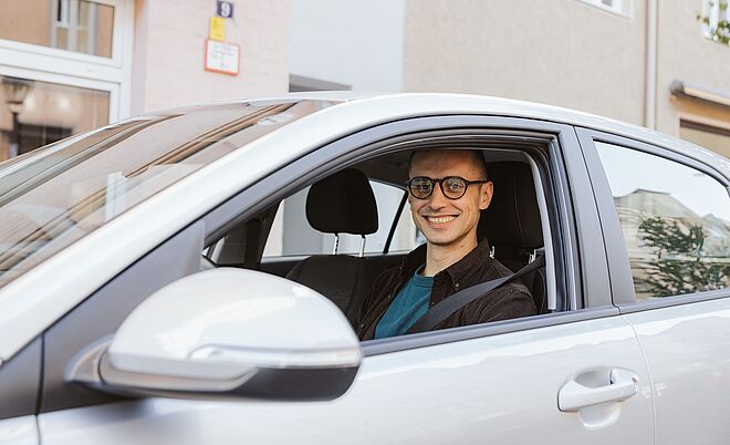 Mann sitzt am Steuer eines Carsharing Autos, Weiterleitung zu Einsteiger-Tarif
