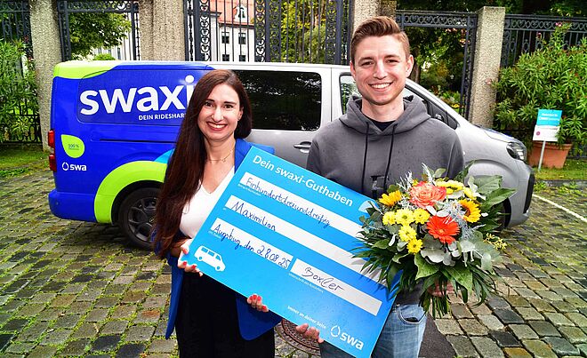 swa Projektleiterin Julia Boxler überreicht dem 33.333 swaxi Kunden Maximilian Fahrtguthaben.