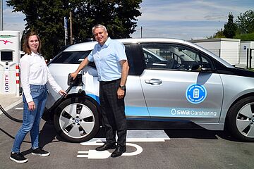 Personen stecken E-Autos ein, - Ein Klick auf das Bild führt zur vergrößerten Fotoansicht.