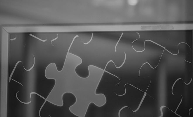 Darstellung eines Puzzles in einem Bilderrahmen mit dunkelgrauen Teilen und einem hellgrauen Puzzleteil.