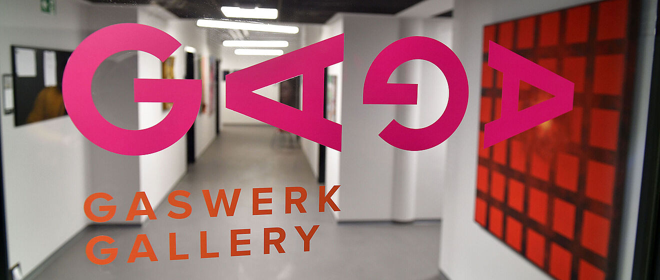 Flur mir Gemälden an der Wand. Im Vordergrund ist der Aufdruck "GAGA Gaswerk Gallery". Weiterverlinkung auf Gaswerk offene Ateliers 2024 Newsartikel