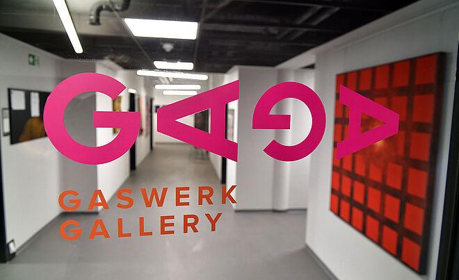 Flur mir Gemälden an der Wand. Im Vordergrund ist der Aufdruck "GAGA Gaswerk Gallery". Weiterverlinkung auf Gaswerk offene Ateliers 2024 Newsartikel