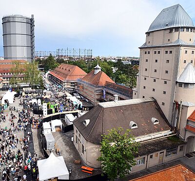 Luftaufnahme einer Menschenmenge mit verschiedenen Ständen auf dem Gaswerksgelände