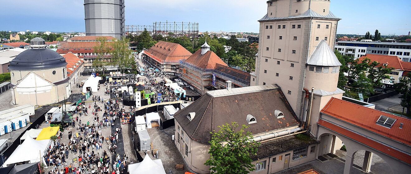 Luftaufnahme einer Menschenmenge mit verschiedenen Ständen auf dem Gaswerksgelände. Weiterverlinkung auf nächsten Schritte 2020 Newsartikel