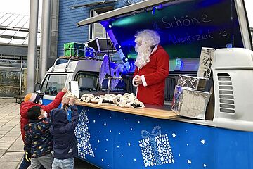 Kinder nehmen sich Geschenk-Beutel vom swa-Wasserbulli. - Ein Klick auf das Bild führt zur vergrößerten Fotoansicht.
