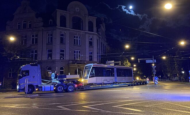 LKW fährt am Roten Tor mit einem Straßenbahnwagen auf dem Anhänger. 