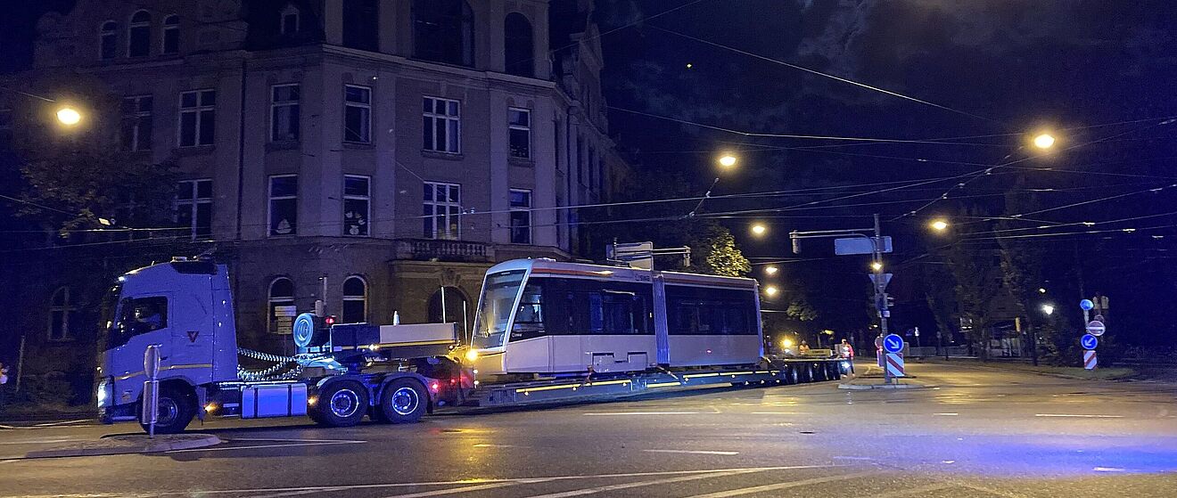 LKW fährt am Roten Tor mit einem Straßenbahnwagen auf dem Anhänger.