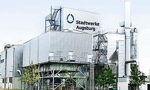 Grüner Feldweg mit Biomasse-Heizkraftwerk und einem roten Auto im Hintergrund. Link zu einem Pop Up mit Infos zu Industriebau