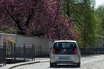 Swa Carsharing Auto in der Stadt auf einem Weg, neben dem sich Kirschblütenbäume und ein Fluss befinden. - Ein Klick auf das Bild führt zur vergrößerten Fotoansicht.