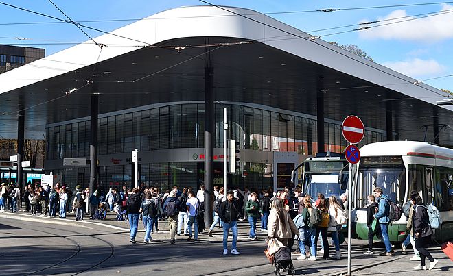 Menschenmenge läuft an der Haltestelle Königsplatz. Es stehen einige Straßenbahnen an den Stationen