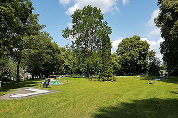 Große grüne Wiese mit Bäumen im Hintergrund und einer Minigolfanlage. Ein Klick sorgt für eine Großansicht des Bildes.