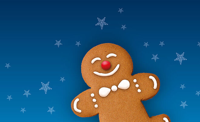 Lächender Lebkuchenmann mit Schneeflocken im Hintergrund.