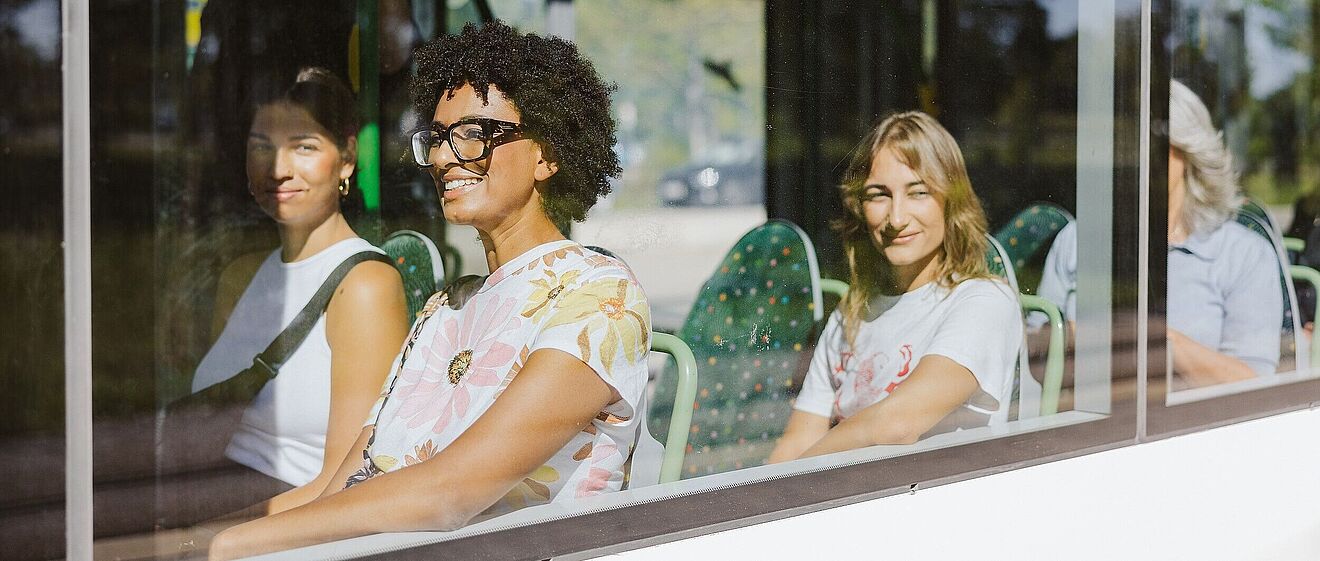 Frauen sitzen in Straßenbahn und lächeln