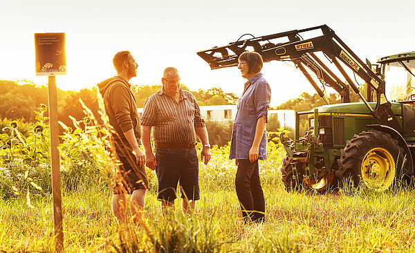 Header: Personen stehen auf Feld