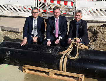 Drei Personen auf einer Baustelle zum Ausbau des Fernwärmegebiets