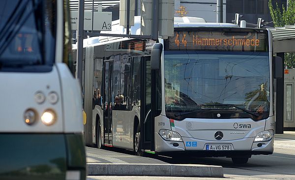 Ein Bus von den Stadtwerken Augsburg hält am Königsplatz. Links seitlich befindet sich eine Straßenbahn.