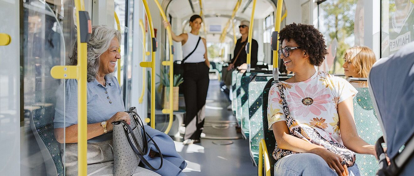 Zwei Frauen lächeln sich in einer Straßenbahn an