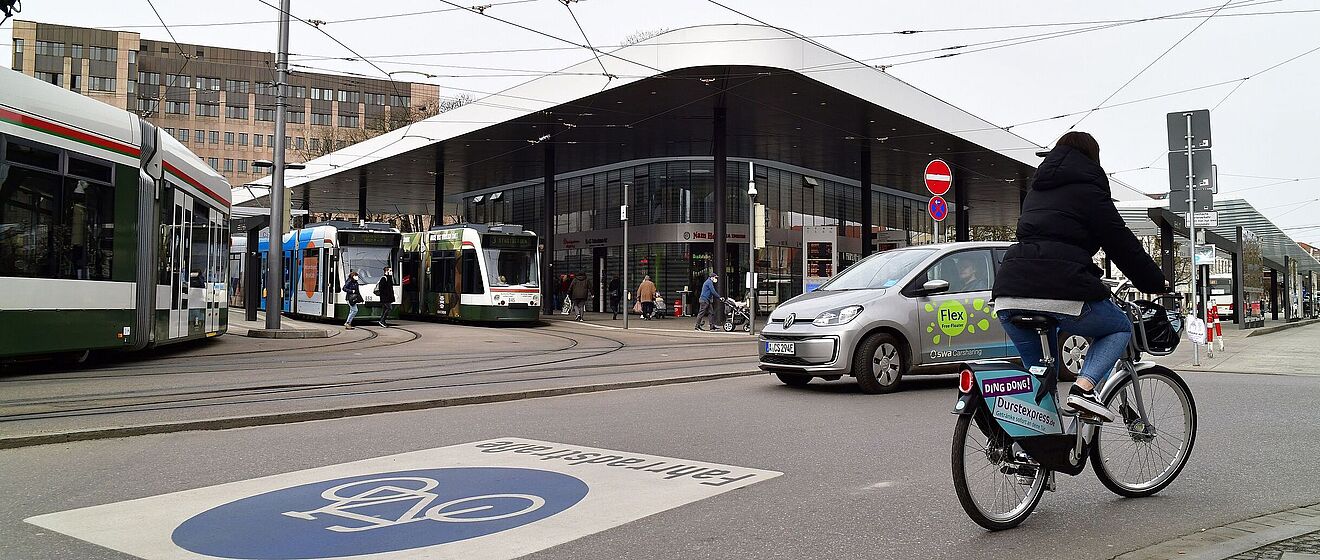 Foto vom Kö mit Bussen, einem Leihrad, einem swa Carsharing Auto und Trams.