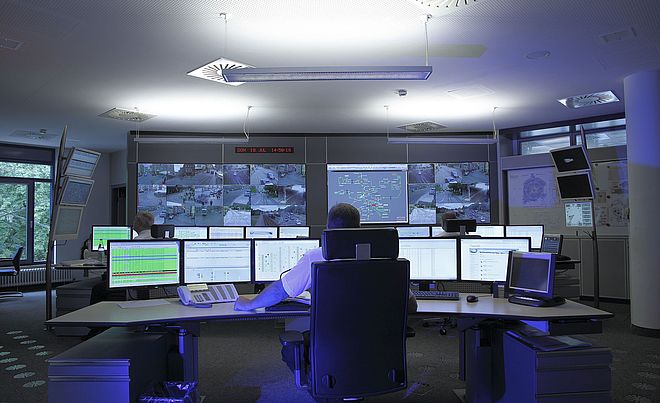 Ein Leitwarte von Hinten mit sehr vielen Bildschirmen vor ihm. Auf den Displays sind LIVE-Überwachungsaufnahmen von Straßenbahnen und Daten zu den Linien zu sehen zusammen mit vielen anderen Anzeigen.