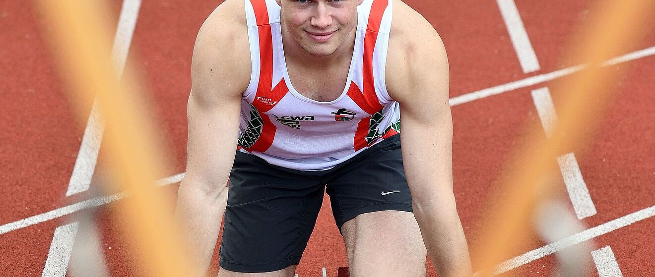Aleksandar Askovic (swa Sportler) befindet sich in der Startposition zum Sprint und blickt in die Kamera.