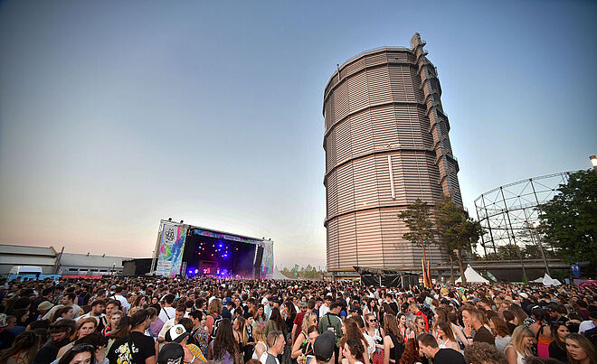 Menschenmenge auf dem Gaswerk beim Modular Festival. Im Hintergrund ist eine Bühne und der große Gasbehälter. Weiterverlinkung auf Modular 2023 Newsartikel