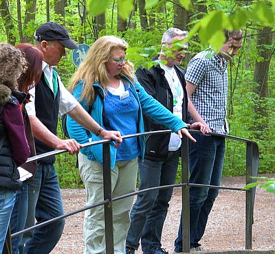 Teilnehmer der Radltour stehen im Wald an einer Brücke.