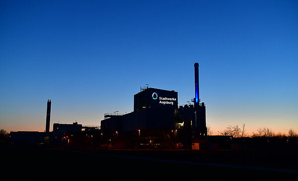Biomasse Heizkraftwerk mit Stadtwerke Augsburg Logo bei Nacht