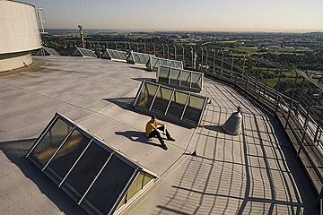 Mann sitzt auf Hausdach. - Ein Klick auf das Bild führt zur vergrößerten Fotoansicht.