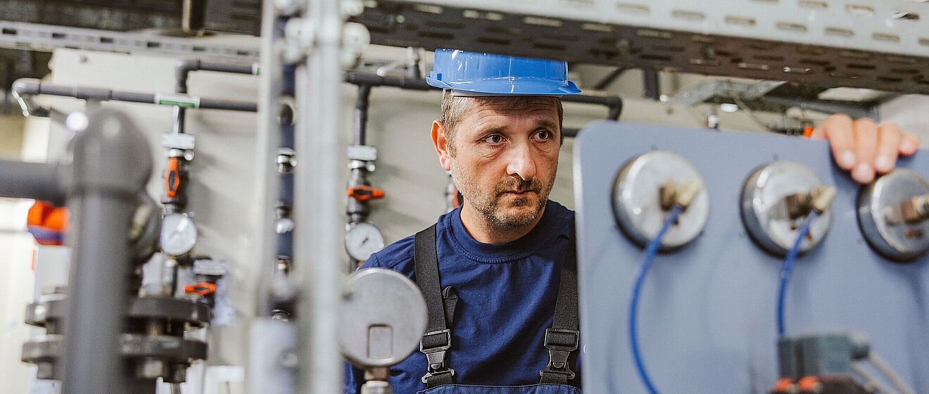 Mitarbeiter prüft Messgeräte. Link zu einem Pop-Up mit Informationen zu Contracting Wärme und Kälte für Kommunen