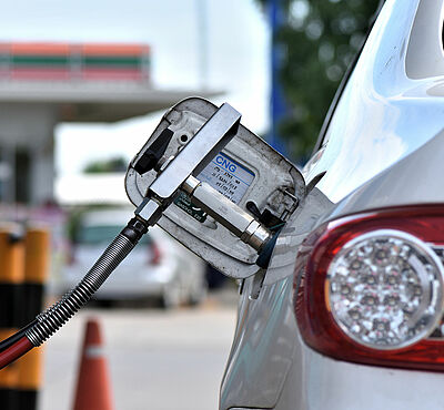 Filling CNG fuel tank at a gas station. Tankschlauch steckt in einem Auto. Im Hintergrund ist der Tankdeckel mit der Kennzeichnung "CNG"
