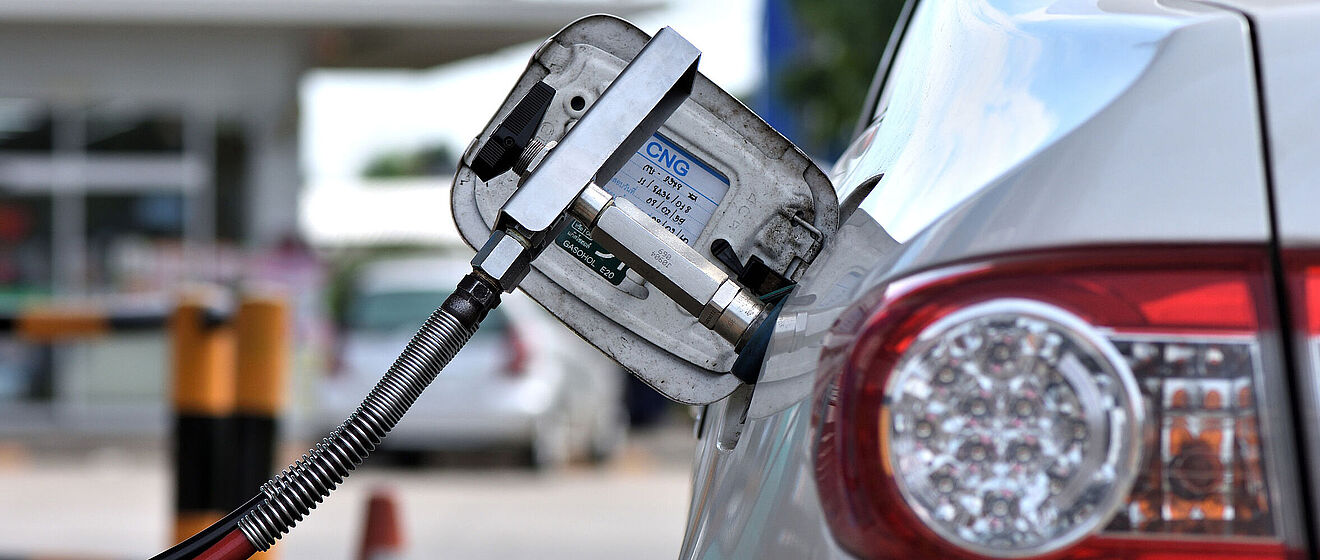 Tankschlauch steckt in einem Auto. Im Hintergrund ist der Tankdeckel mit der Kennzeichnung "CNG"