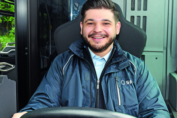 Mann welcher einen Bus fährt und freundlich in die Kamera Blickt. - Beim anklicken wird das Bild vergrößert.