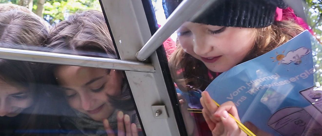 Kinder schauen durch ein Dachfenster nach unten, Weiterleitung zu Der Wasserweg 