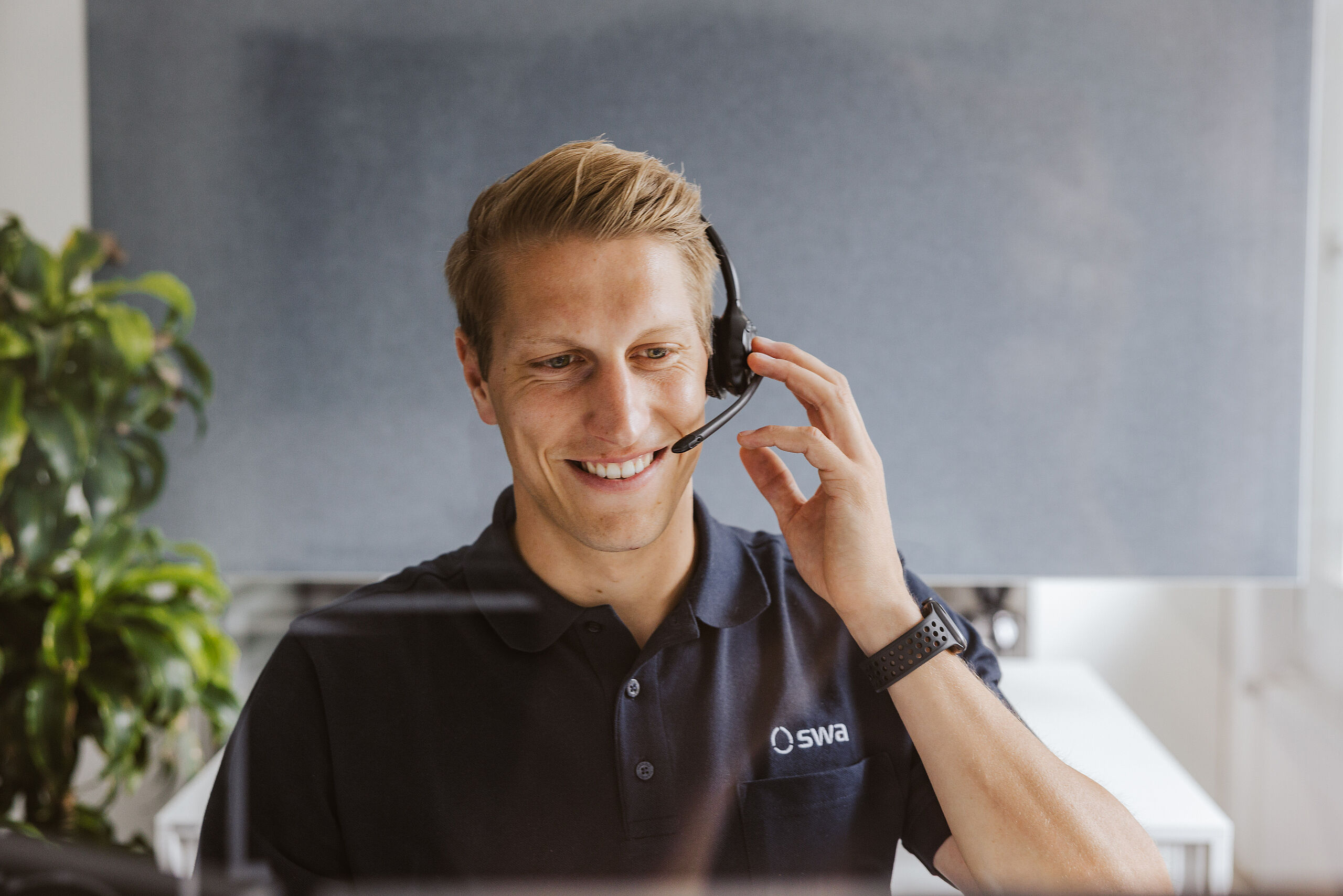 Lachender Stadtwerke Augsburg Mitarbeiter mit Headset auf dem Kopf im Büro